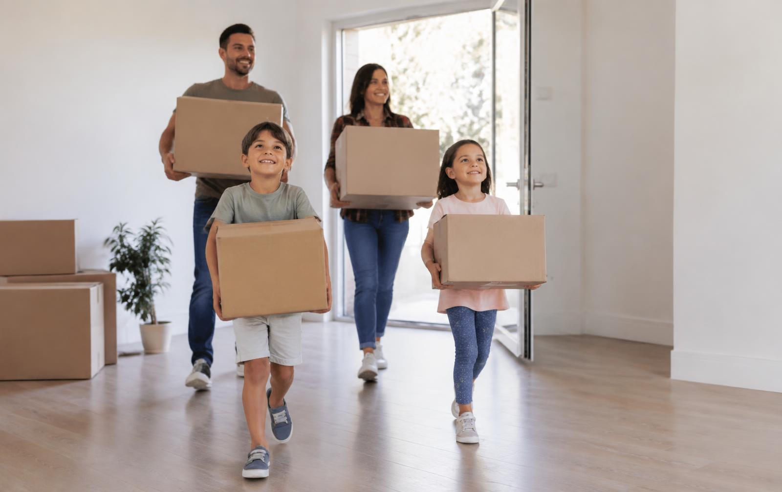 A family carrying moving boxes into a bright new home